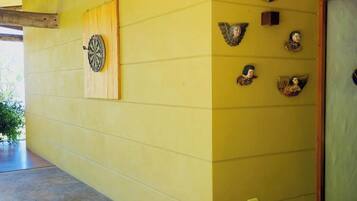 A yellow wall with a dartboard and decorative angel head sculptures.