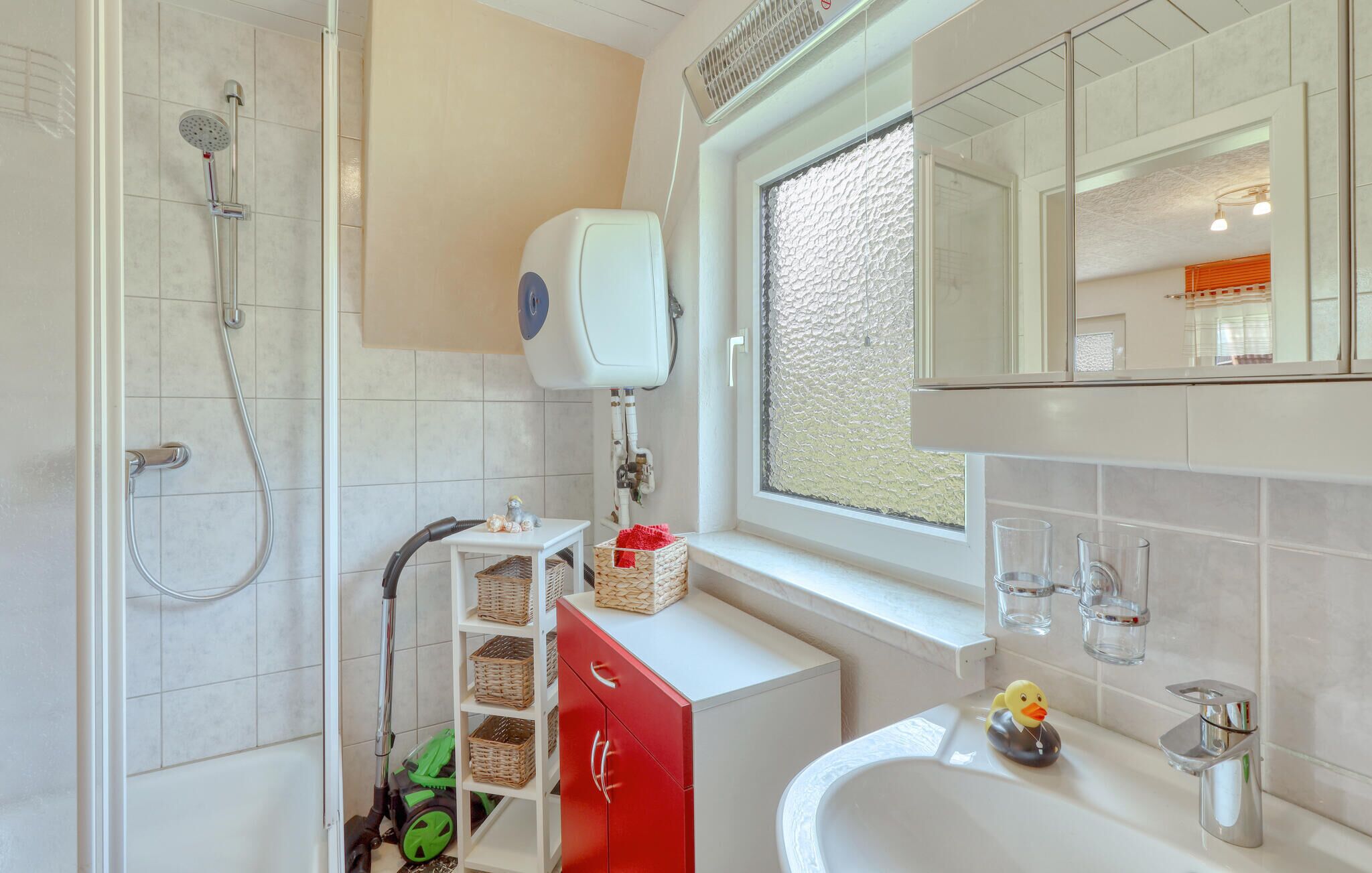 A modern bathroom with a shower, a toilet, a sink, and a window with a textured view.