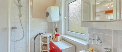 A modern bathroom with a shower, a toilet, a sink, and a window with a textured view.