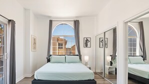 A modern bedroom with a large bed, a mirror, and a view of the outside.
