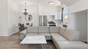 A modern kitchen with white cabinets, stainless steel appliances, and a dining area with a white table and chairs.