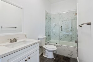 Ein Badezimmer mit weißem Waschtisch, Toilette und einer Duschkabine.
