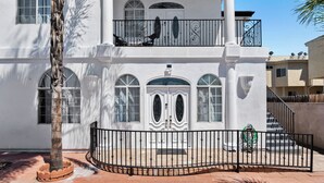 A two-story building with a balcony, large windows, and a gated entrance.