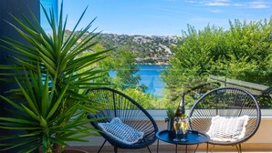 A balcony with two wicker chairs, a small table, and a potted plant. - Luxurious home in Bakarac with private swimming pool, can be inside or outside (Bakarac)