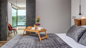 A modern bedroom with a large bed, a wooden tray with breakfast items, a red chair, and a view of the outdoors. - Luxurious home in Bakarac with private swimming pool, can be inside or outside (Bakarac)