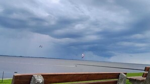 Un banc donnant sur une étendue d’eau, sous un ciel nuageux.