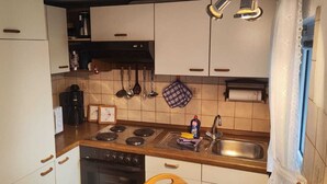 Une cuisine de taille réduite avec des meubles blancs, une cuisinière, un évier et un lave-vaisselle.