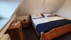Une petite chambre à coucher accueillante, avec un lit en bois, une table de chevet et une commode.