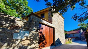 Un edificio de piedra con puerta de madera, una ventana pequeña y un cartel en la pared.