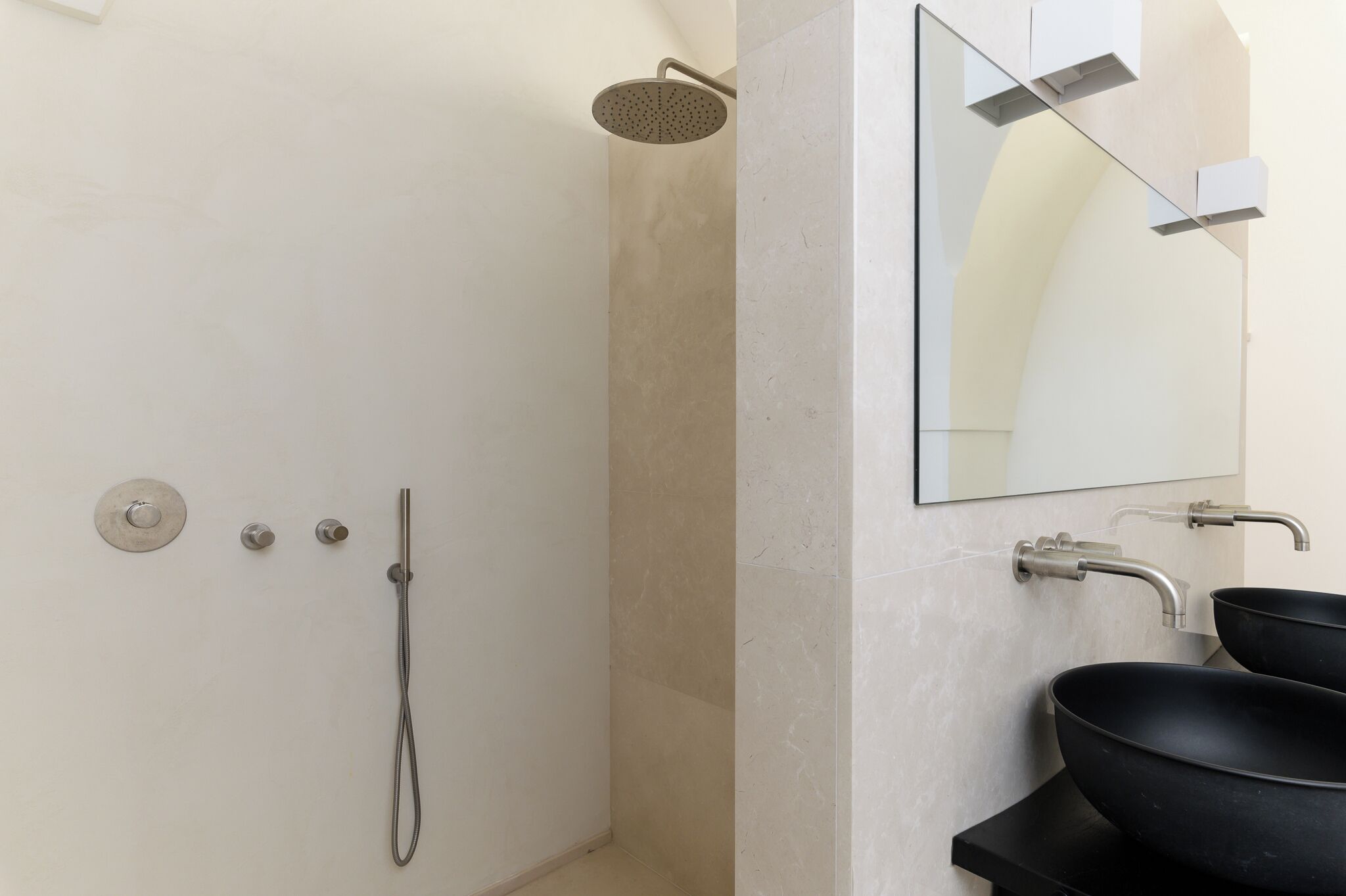 A modern bathroom with a shower, two sinks, and a large mirror.