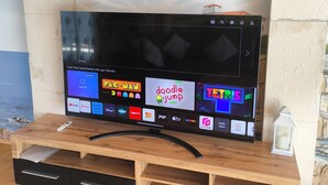 A flat-screen TV on a wooden stand with a wooden drawer below it.