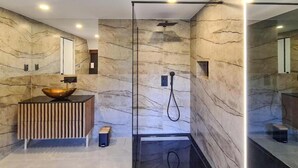 Une salle de bain moderne avec un mur en pierre, un meuble-lavabo en bois et une cabine de douche en verre.