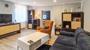 Un salon moderne comprenant un canapé, une table basse, un téléviseur et une bibliothèque.