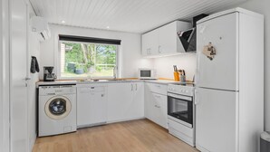 Una cocina compacta equipada con lavadora, microondas, horno y refrigerador.