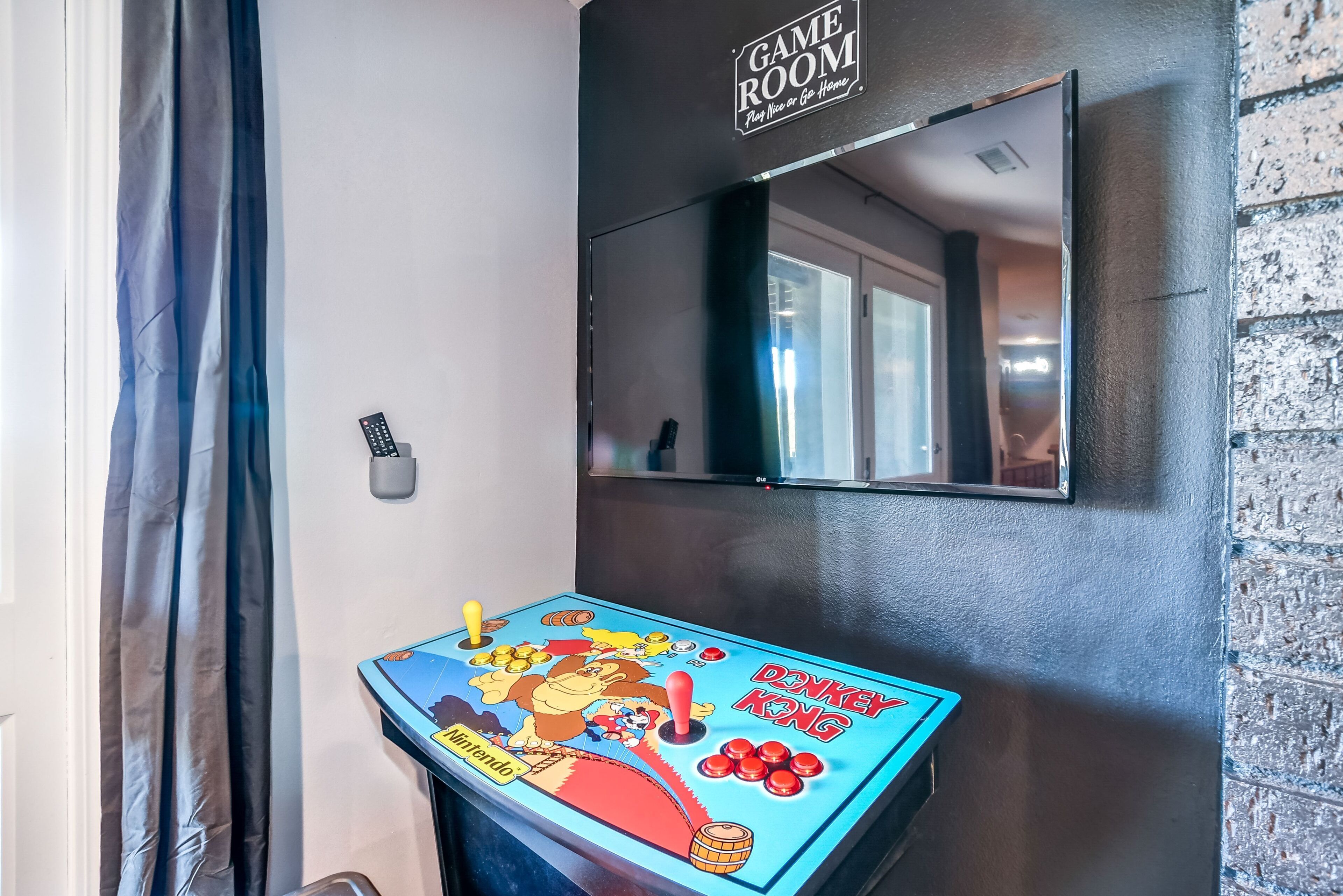 Een kamer met een Nintendo Donkey Kong spelcomputer, een spiegel en een bord waarop staat 'GAME ROOM'.