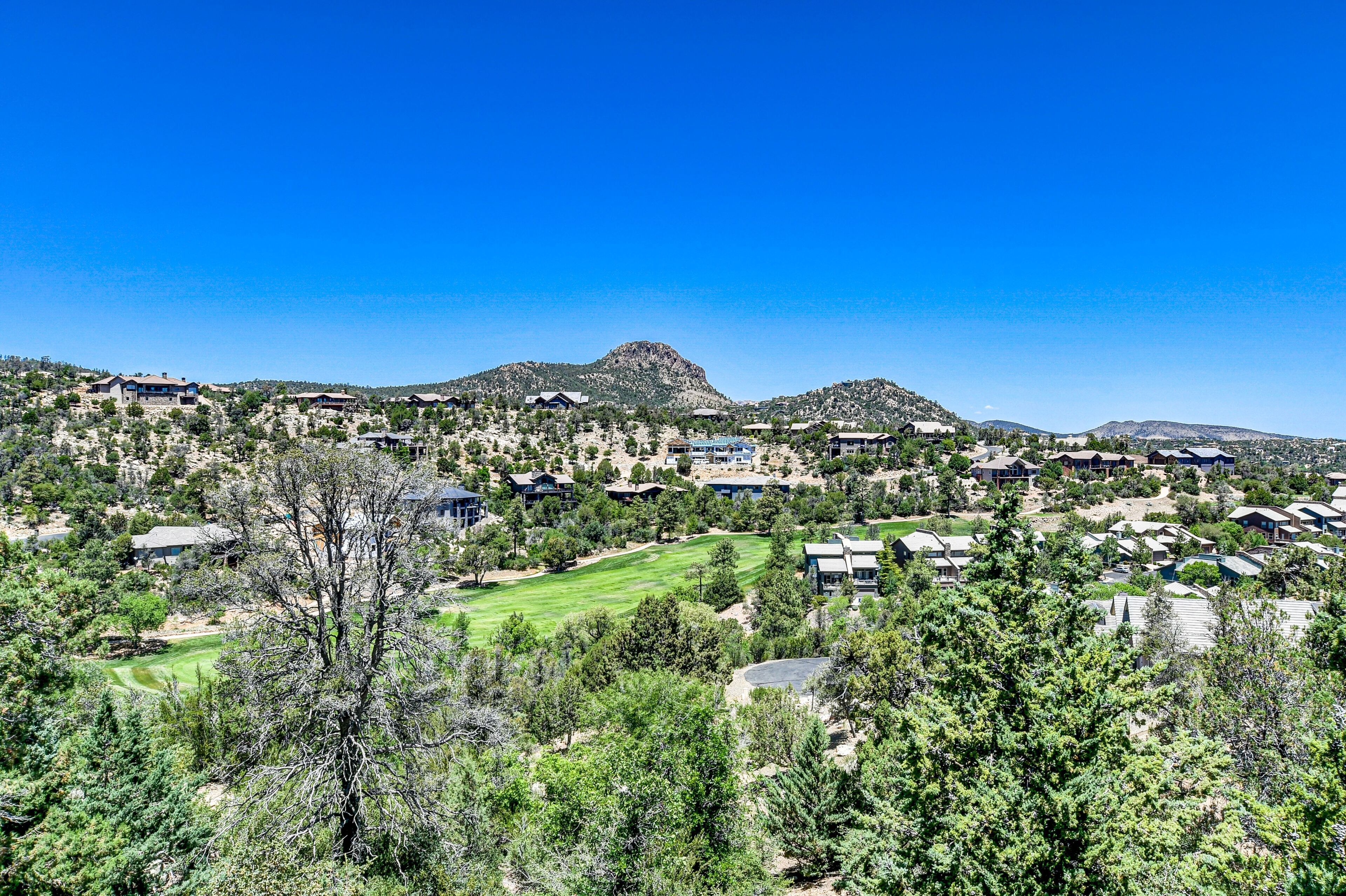 A residential area with houses, a golf course, and mountains in the background.
