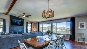 A spacious living area with a large window, a fireplace, and a dining table set for four. - 5BR Group Escape • Game Room • Views • Sleeps 12 • 10 mins to DT • EV charger (Prescott)