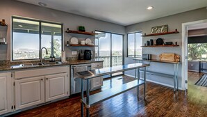 A modern kitchen with a large window, stainless steel appliances, and wooden shelves. - 5BR Group Escape • Game Room • Views • Sleeps 12 • 10 mins to DT • EV charger (Prescott)