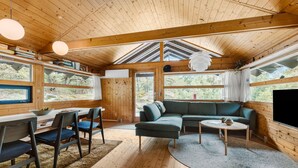 A cozy cabin interior with a dining area, a sofa, and a TV.