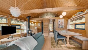 A cozy cabin interior with a sofa, a dining table, a TV, and a fireplace.