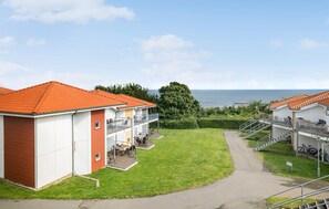 Ein Küstenhotel mit rotem Ziegeldach, einem grünen Rasen und Meerblick.