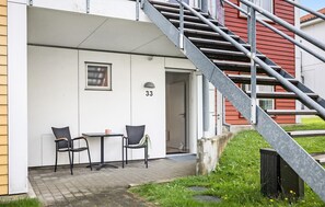 Ein Gebäude mit einer Treppe, die zu einem Eingang führt, einer Tür mit der Nummer 33 und zwei Stühlen sowie einem kleinen Tisch davor.