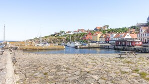 A harbor with boats, a stone quay, and colorful buildings in the background.