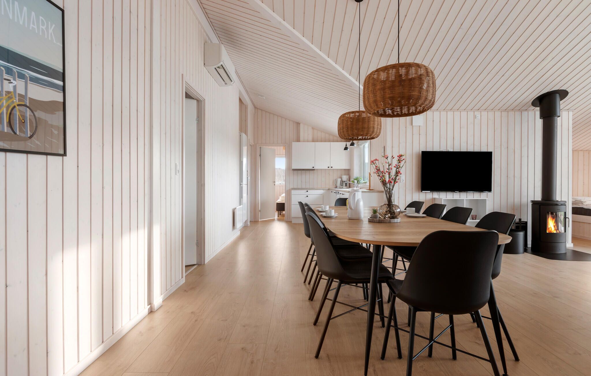 Une cuisine moderne avec des meubles blancs, un coin repas doté d’une table en bois et de chaises noires, ainsi qu’une grande cuisinière noire.