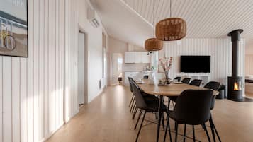 Une cuisine moderne avec des meubles blancs, un coin repas doté d’une table en bois et de chaises noires, ainsi qu’une grande cuisinière noire.
