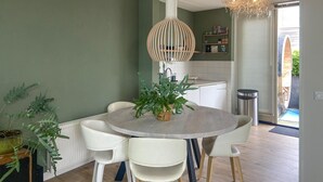 A dining area with a round table, white chairs, and a hanging light fixture.