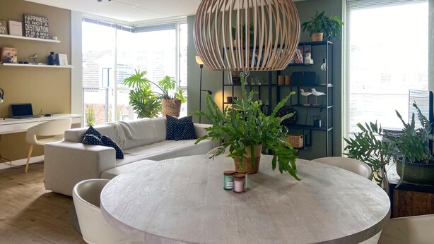 A modern living room with a round dining table, a sofa, and a bookshelf.