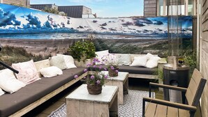 A rooftop patio with a mural of a beach scene, outdoor seating, and a water feature.