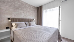 Un dormitorio moderno con una cama grande, una mesita de noche y un ventanal con cortinas.