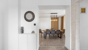 Un comedor moderno con piso de mármol, un espejo redondo y un separador de madera.