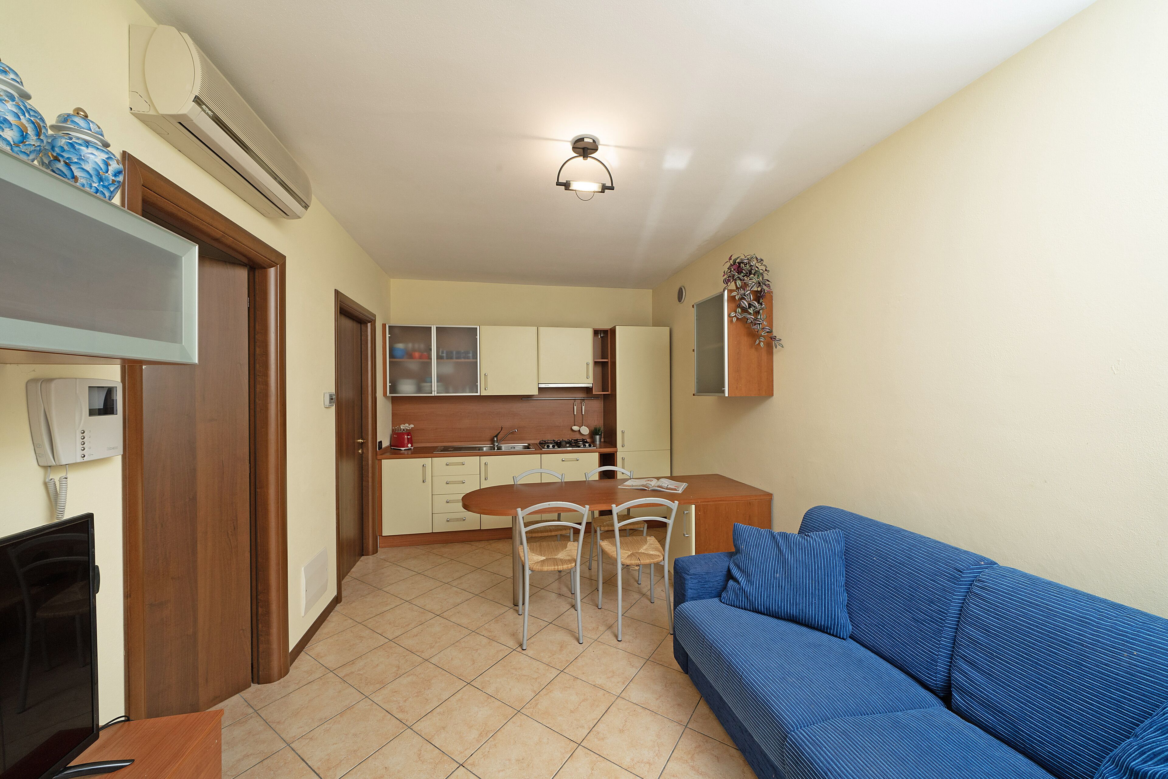 A compact living space with a kitchenette, a dining area, and a seating area with a sofa.