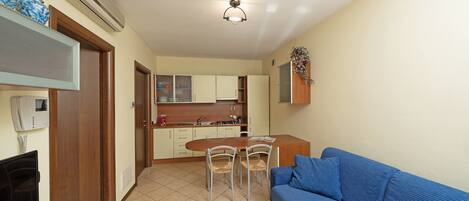 A compact living space with a kitchenette, a dining area, and a seating area with a sofa.