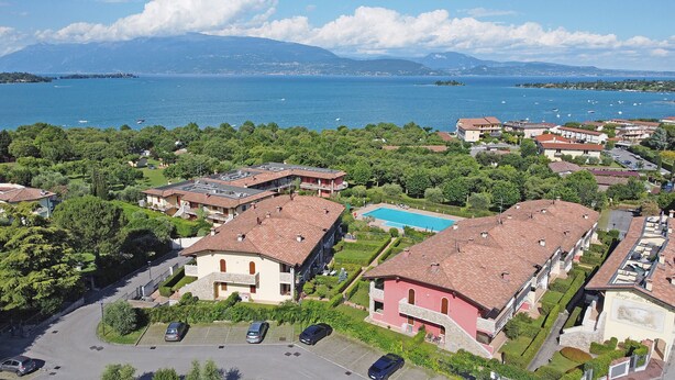An aerial view of a residential area with buildings, a swimming pool, and a lake. - Borgo delle Colline 19 by Wonderful Italy (Manerba del Garda)