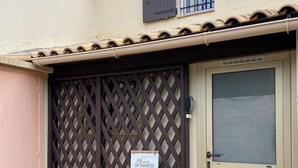 A house with a brown lattice gate, a welcome mat, and a sign that reads "Maison du Bonheur". - Villa Club Portissol (Sanary-sur-Mer)