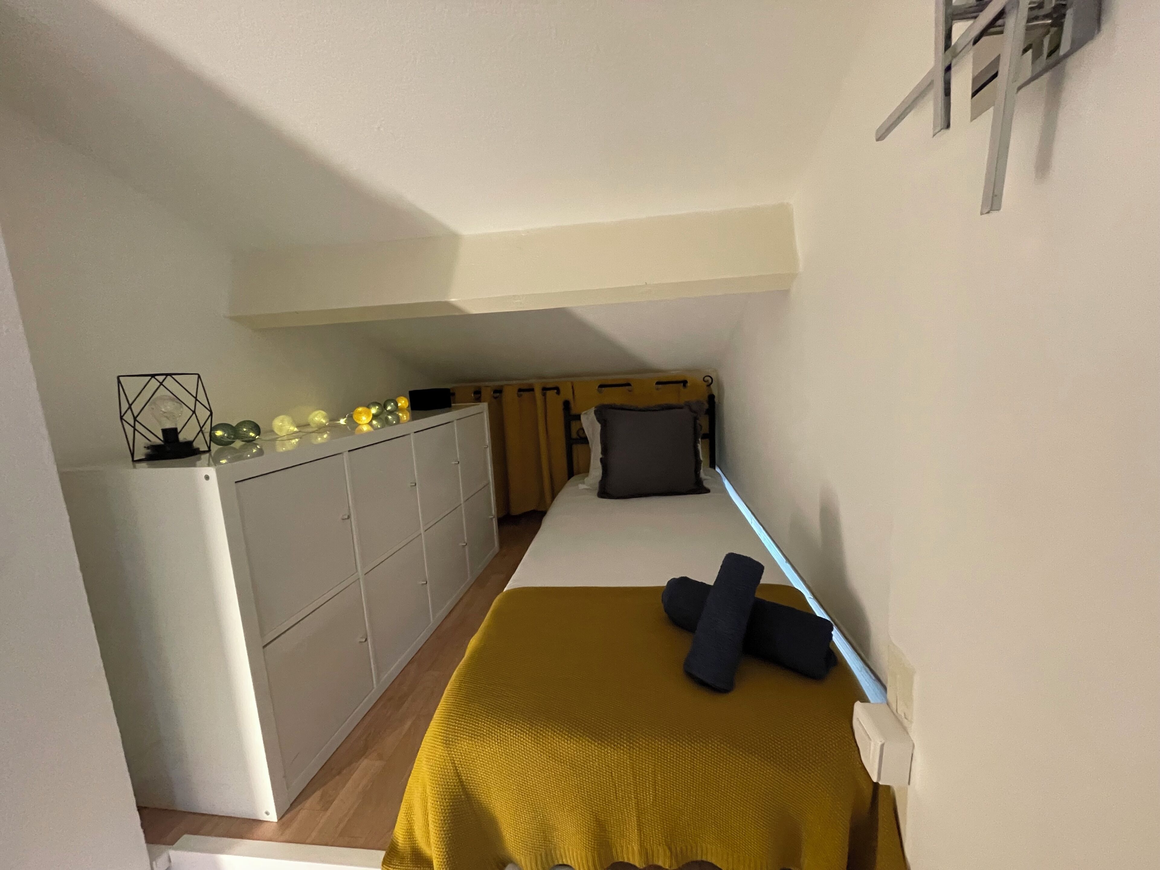 Ein kleines Zimmer mit einem Bett, einem Schreibtisch und einem Kleiderschrank.
