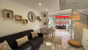 A modern living room with a black sofa, a round glass coffee table, and a dining area with a table and chairs. - Villa Club Portissol (Sanary-sur-Mer)