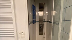 A modern bathroom with a glass-enclosed shower, white tiled walls, and a blue accent wall. - Villa Club Portissol (Sanary-sur-Mer)