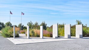 A memorial with four stone pillars and two flags. - 3 bedroom awesome home in Créances (Créances)