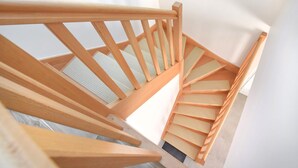 A wooden spiral staircase with a handrail and a light-colored wall in the background. - 3 bedroom awesome home in Créances (Créances)
