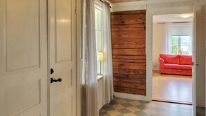 Un couloir avec un sol à carreaux, un mur en bois et un canapé rouge à l’arrière-plan.