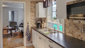 Une cuisine moderne avec un plan de travail noir, des armoires blanches et un micro-ondes encastré.