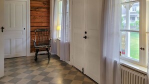 Un couloir avec un sol à carreaux, des portes blanches, un mur en bois et une chaise.