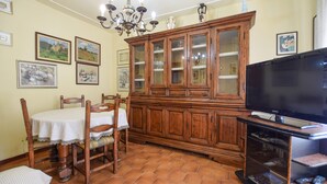 Un comedor con un armario de madera, un televisor y una mesa con sillas.