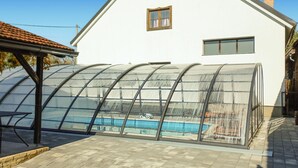 Ein Haus mit überdachtem Pool und einer Terrassenfläche.