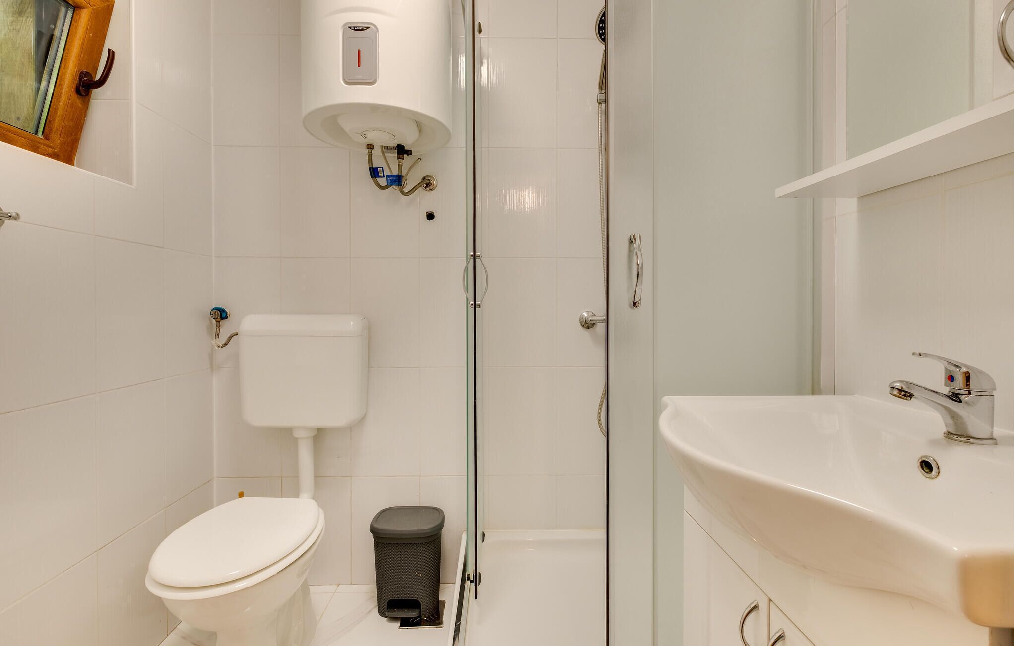 A bathroom with a toilet, a glass-enclosed shower, and a sink.