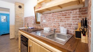 Eine Küche mit Backsteinwand, Holzschränken, einer Edelstahl-Spüle und einem Messerblock.